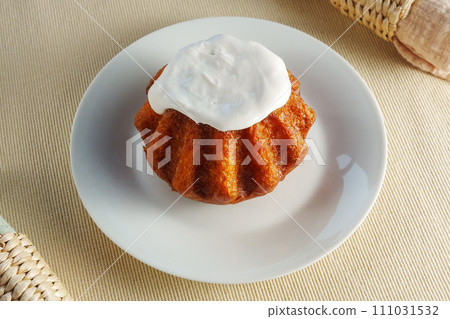 A tantalizing cupcake sits on a delicate plate, adorned with a fluffy mountain of whipped cream topping. A tantalizing cupcake sits on a delicate plate, adorned with a fluffy mountain of whipped cream topping. 111031532