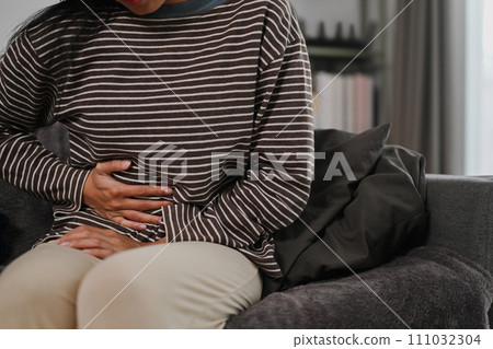 Unhappy young woman holding belly suffering from abdominal pain, digestive problems. Health care concept 111032304