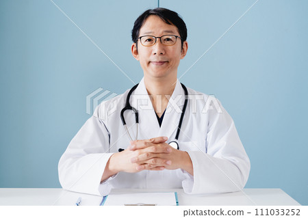 Middle-aged male doctor wearing a white coat Middle-aged male doctor wearing a white coat 111033252