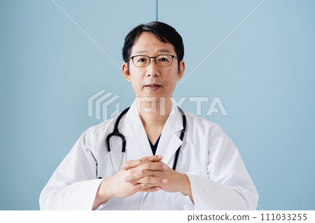 Middle-aged male doctor wearing a white coat Middle-aged male doctor wearing a white coat 111033255