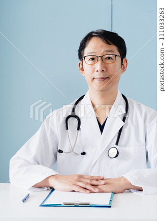 Middle-aged male doctor wearing a white coat Middle-aged male doctor wearing a white coat 111033263