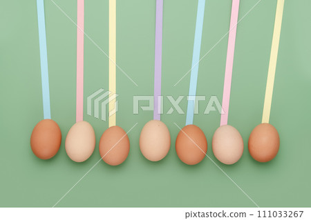 Row of different shade eggs with fun leading geometric lines on green background. Copy space simple pastel rustic background for traditional Easter holiday card 111033267