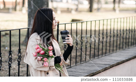 Coffee Culture, takeaway coffee cup in female hand related to coffee culture, casual meetings, or breaks during the workday. Woman with Coffee and Tulips Enjoying City Park 111033886