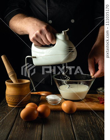 Chef is preparing a culinary dish in the kitchen with milk and eggs. Concept of preparing a delicious lunch on the kitchen table in a restaurant or hotel Chef is preparing a culinary dish in the kitchen with milk and eggs. Concept of preparing a delicious lunch on the kitchen table in a restaurant or hotel 111035170