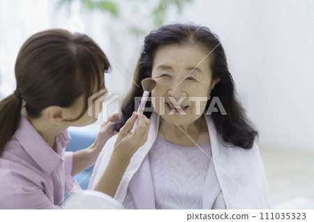 Senior woman receiving beauty treatment at home 111035323