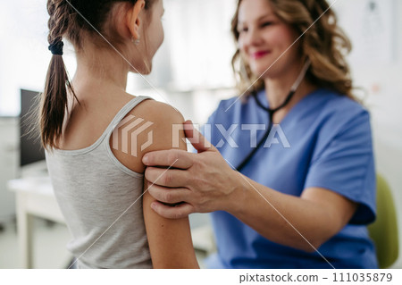 Orthopedist examines the spine, posture, and spinal deformities of little girl. Girl visiting paediatrician for annual preventive exam. Concept of preventive health care for children. 111035879