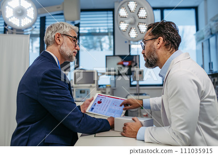 Pharmaceutical sales representative presenting new medication to doctor in medical building, holding box with medication samples. 111035915