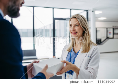 Pharmaceutical sales representative presenting new medication to doctor in medical building. 111035992