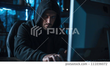 Hacker in a dark hoody sitting in front of a computer Hacker in a dark hoody sitting in front of a computer 111036072