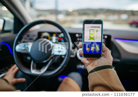 Close up of man using electric vehicle charging app, checking battery level on smart phone. Charging apps for monitoring electricity usage, locating charging stations. 111036177