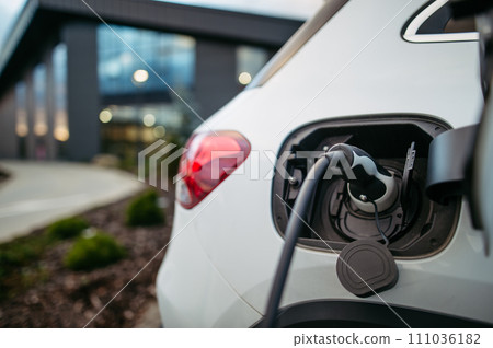 Close up electric car charging in front of office building. Charging at work, workplace. 111036182
