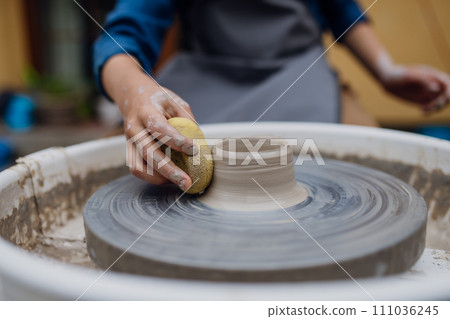 Close up woman doing pottery on pottery wheel. Child creative activities and art. Boy making pottery with mom, having fun. Happy family moment. Close up woman doing pottery on pottery wheel. Child creative activities and art. Boy making pottery with mom, having fun. Happy family moment. 111036245