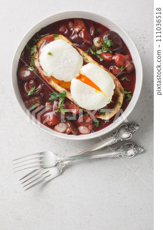 Eggs meurette or poached eggs with red wine sauce closeup on the plate. Vertical top view Eggs meurette or poached eggs with red wine sauce closeup on the plate. Vertical top view 111036518