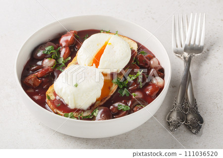 Oeufs en meurette is a traditional dish from Burgundian cuisine based on poached eggs and meurette sauce or bourguignon sauce closeup on the plate. Horizontal 111036520