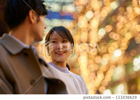 A woman happily talking to a man in an illuminated cityscape 111036629
