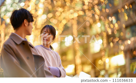 A woman happily talking to a man in an illuminated cityscape A woman happily talking to a man in an illuminated cityscape 111036633