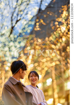 A woman happily talking to a man in an illuminated cityscape 111036634