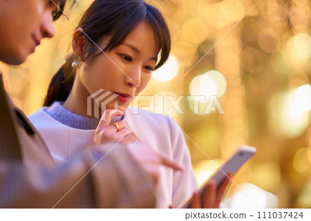 A woman and a man happily operate smartphones A woman and a man happily operate smartphones 111037424