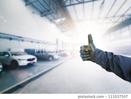 Car mechanic signaling OK with a confident thumbs up gesture inside a car maintenance service center Car mechanic signaling OK with a confident thumbs up gesture inside a car maintenance service center 111037507
