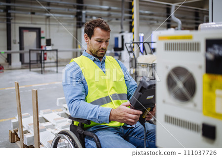 Portrait of man in wheelchair working in modern industrial factory, scanning with scanner. Concept of workers with disabilities, accessible workplace for employees with mobility impairment. 111037726