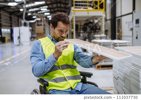Portrait of man in wheelchair working in modern industrial factory, scanning with scanner. Concept of workers with disabilities, accessible workplace for employees with mobility impairment. 111037730