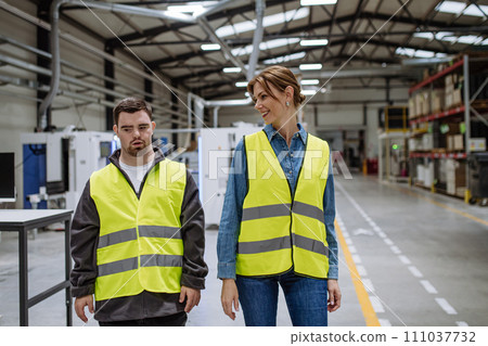 Young man with Down syndrome working in warehouse, colleague talking with him. Concept of workers with disabilities, support in workplace. 111037732