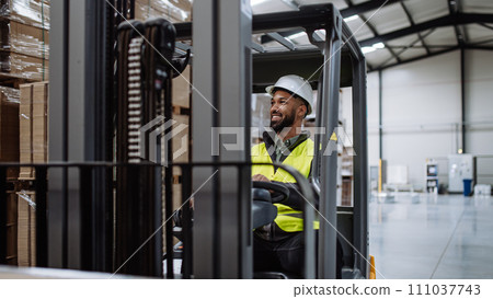Portrait of warehouse worker driving forklift. Warehouse worker preparing products for shipmennt, delivery, checking stock in warehouse. Banner with copy space. Portrait of warehouse worker driving forklift. Warehouse worker preparing products for shipmennt, delivery, checking stock in warehouse. Banner with copy space. 111037743