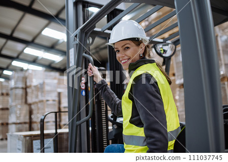 Female warehouse worker driving forklift. Warehouse worker preparing products for shipmennt, delivery, checking stock in warehouse. Banner with copy space. Female warehouse worker driving forklift. Warehouse worker preparing products for shipmennt, delivery, checking stock in warehouse. Banner with copy space. 111037745