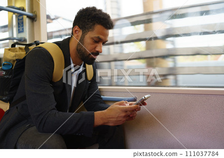 Handsome man traveling by city train, scrolling on a smartphone. Single man using dating app. Handsome man traveling by city train, scrolling on a smartphone. Single man using dating app. 111037784