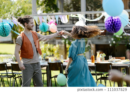 Couple in love dancing at the family garden party. A family gathering to celebrate a birthday. Couple in love dancing at the family garden party. A family gathering to celebrate a birthday. 111037829