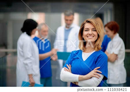 Portrait of beautiful female doctor standing in front of team of doctors. Colleagues, doctors team discussing patients diagnosis. Portrait of beautiful female doctor standing in front of team of doctors. Colleagues, doctors team discussing patients diagnosis. 111038421