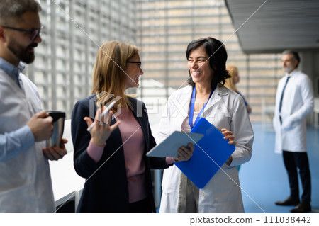Doctors talking to pharmaceutical sales representative, presenting new pharmaceutical product. Hospital manager talking with doctors team. 111038442