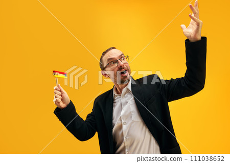 Jewish man in his 30s, in glasses, yarmulke joyfully posing with wooden noisemaker, gragger against yellow studio background Jewish man in his 30s, in glasses, yarmulke joyfully posing with wooden noisemaker, gragger against yellow studio background 111038652