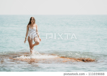 Woman sea yoga. Back view of free calm happy satisfied woman with long hair standing on top rock with yoga position against of sky by the sea. Healthy lifestyle outdoors in nature, fitness concept 111039088