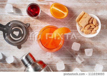 Orange cocktails and a shaker, with a jigger of campari and ice, overhead Orange cocktails and a shaker, with a jigger of campari and ice, overhead 111039093