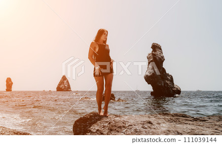 Woman summer travel sea. Happy tourist in hat enjoy taking picture outdoors for memories. Woman traveler posing on the beach at sea surrounded by volcanic mountains, sharing travel adventure journey Woman summer travel sea. Happy tourist in hat enjoy taking picture outdoors for memories. Woman traveler posing on the beach at sea surrounded by volcanic mountains, sharing travel adventure journey 111039144