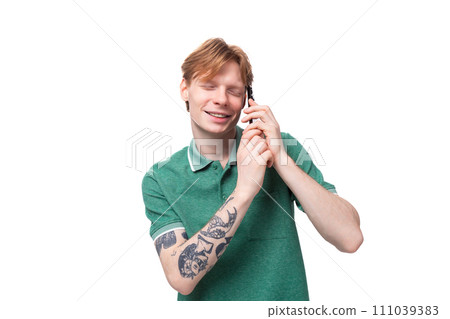 young caucasian man with red hair dressed in a green t-shirt speaks on the phone against the 111039383