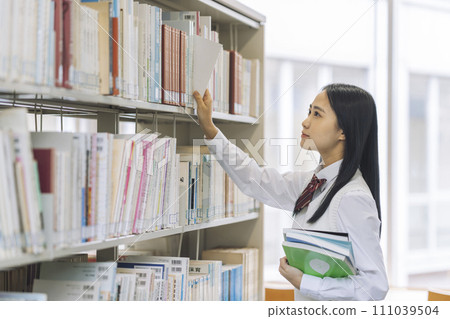 High school girl choosing a book in the library 111039504