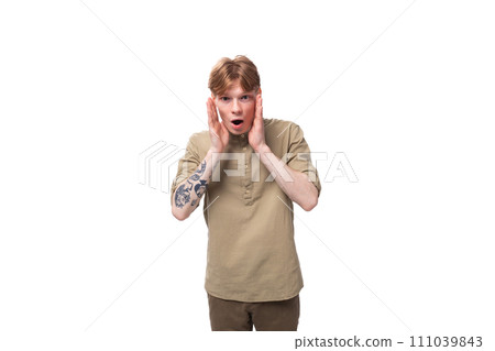 young surprised red-haired man in a beige shirt on a white background 111039843