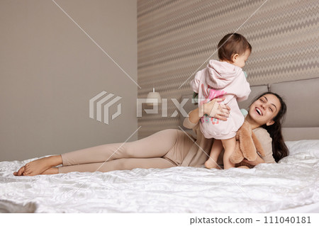 happy mother and her little child daughter playing with bunny toys in bedroom, family having fun happy mother and her little child daughter playing with bunny toys in bedroom, family having fun 111040181