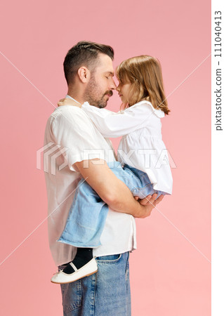 Calm. Portrait of father holds on hands and hugs his little daughter against pink pastel background. Concept of International Day of Happiness 111040413