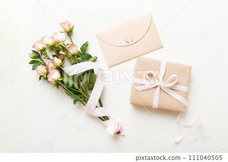 Greeting card mockup with copy space, pink ribbon and roses flowers on colored table background. Flat lay, top view. mother day holiday concept 111040505
