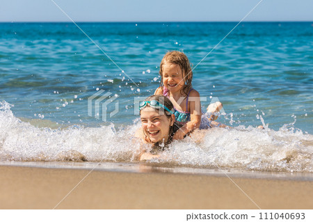 Joyful children playing in the shallow beach waves 111040693