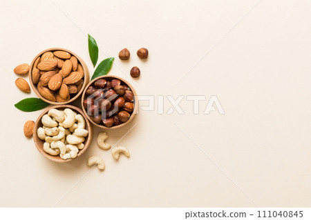 Assortment of nuts in wooden bowl on colored table. Cashew, hazelnuts, walnuts, almonds. Mix of nuts Top view with copy space 111040845