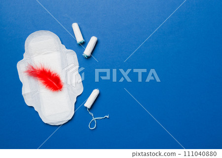 women pads and tampon - sanitary pads lies next to a tampon on an isolated background on a pink and violet background. Women's hygiene and menstrual period concept 111040880