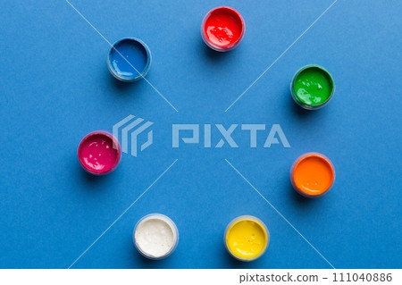 jars with gouache of different colors on Colored background. hobby painting. Top view with empty space. workplace for creativity. home teaching concept drawing 111040886