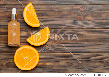 Bottles with orange fruit essential oil on wooden background. alternative medicine top view with copy space Bottles with orange fruit essential oil on wooden background. alternative medicine top view with copy space 111040987