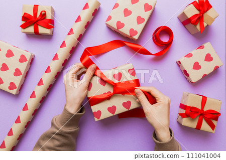 Women hands pack gifts and make decorations for the holiday, top view. Birthday and valentine present Women hands pack gifts and make decorations for the holiday, top view. Birthday and valentine present 111041004