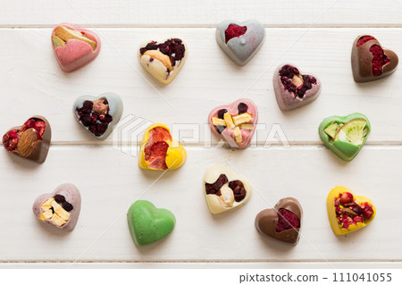 chocolate sweets in the form of a heart with fruits and nuts on a colored background. top view with space for text, holiday concept chocolate sweets in the form of a heart with fruits and nuts on a colored background. top view with space for text, holiday concept 111041055