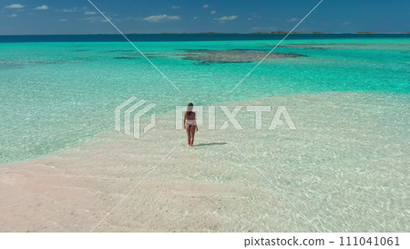 Aerial tropical island beach with coral reef crystal turquoise water. Woman back view standing in sea enjoy beautiful wild nature landscape. Yellow kayak. Summer holiday vacation. D Aerial tropical island beach with coral reef crystal turquoise water. Woman back view standing in sea enjoy beautiful wild nature landscape. Yellow kayak. Summer holiday vacation. D 111041061